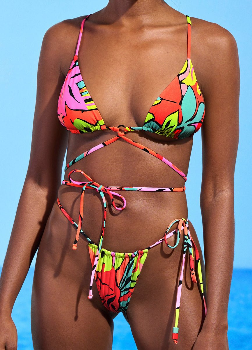 Model in Maaji's Coco Sliding Top and Splashy bottom, a wrap-tie string bikini in a bright tropical leaf print