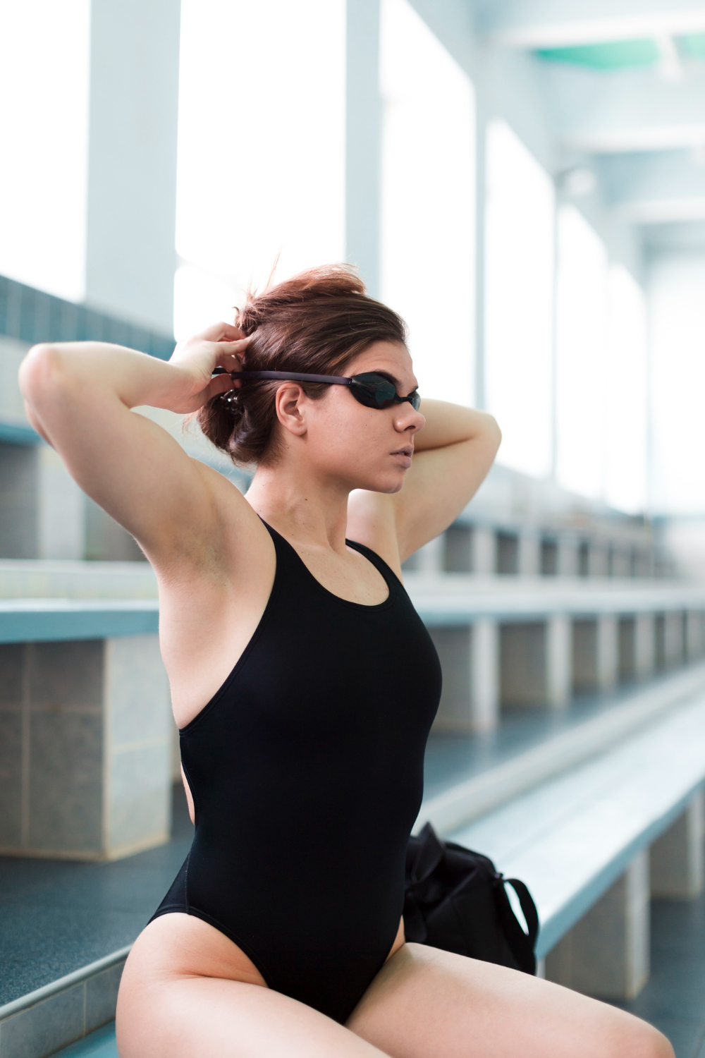 Woman on a swimming pool wearing a black one-piece swimsuit