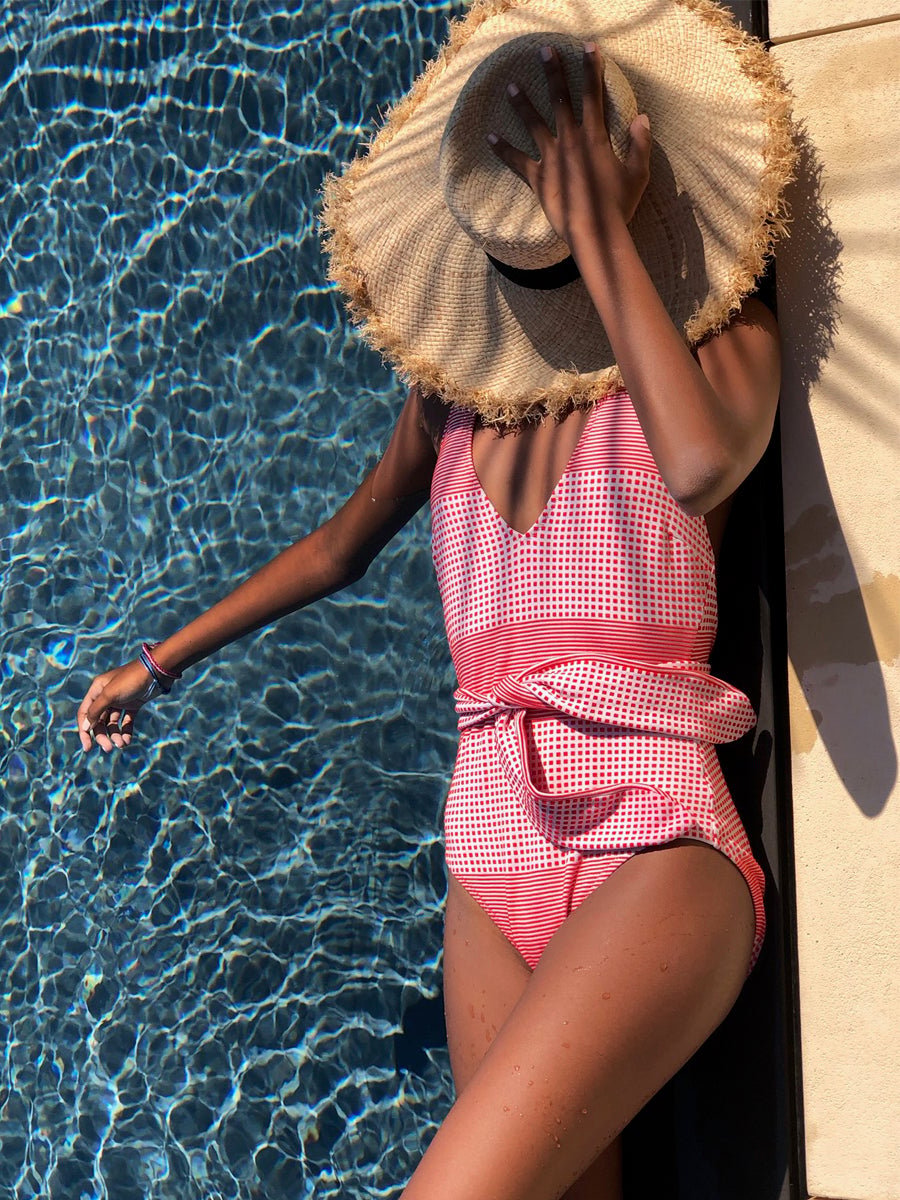 Semira Deep V Belted One Piece in red and white gingham, worn by the pool under a straw hat