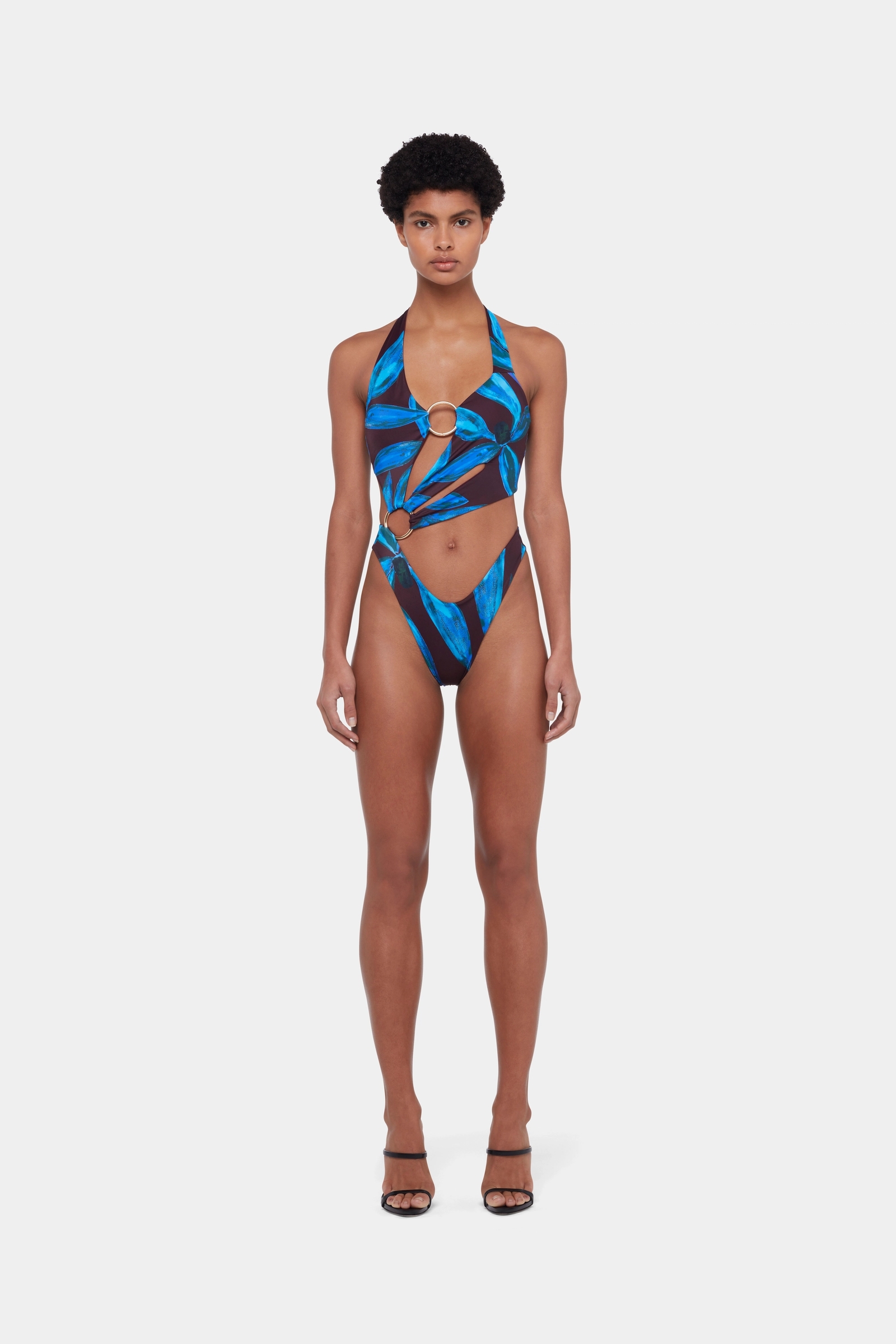 Model in the Sex Wax one-piece by Louisa Ballou in a blue Orchid print with gold rings and cutouts