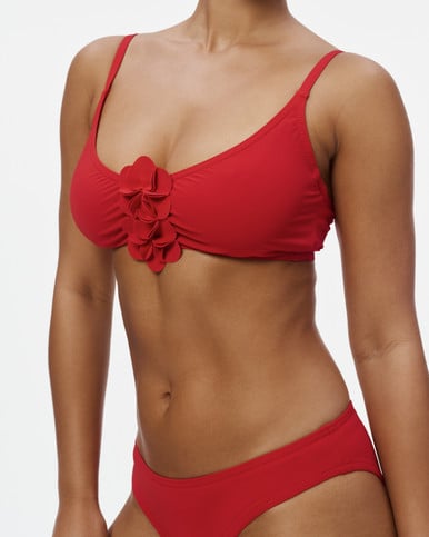 Tess Underwire Top in scarlet with a fabric flower cluster at the bust, close-up on a model with the matching Basics Hip Pant