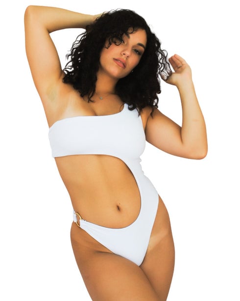 Camila One Piece in white: one-shoulder swimsuit with a side cut-out and a gold ring, worn by a model