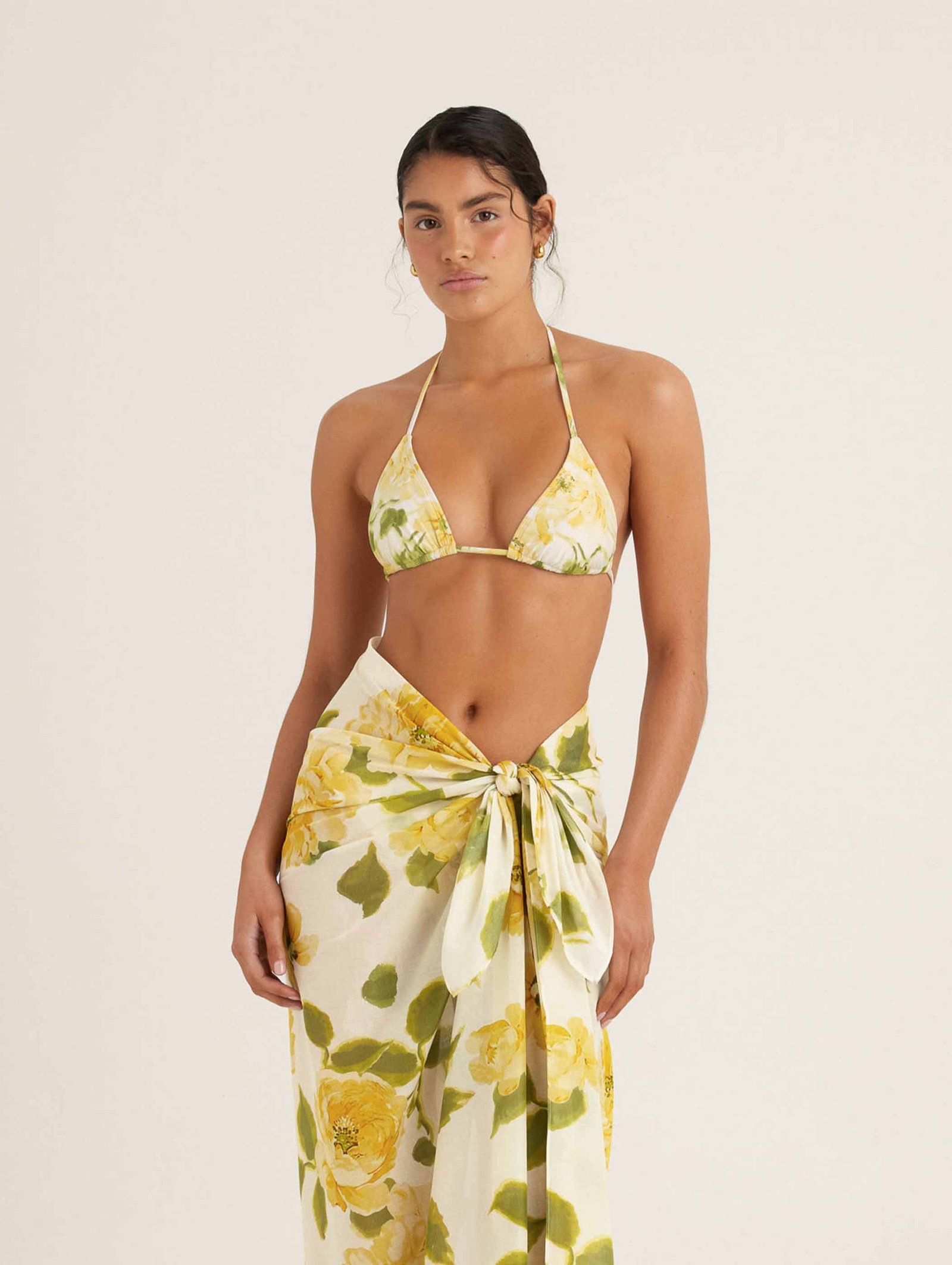 Essential String Tri in Clair De Lune, a yellow rose print, worn with a matching sarong tied at the waist
