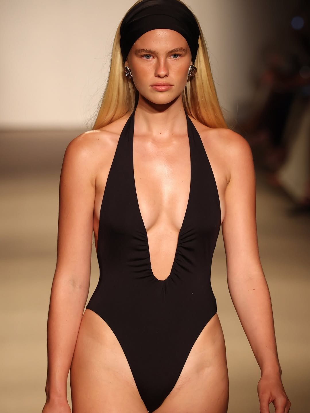 Sleek black Cyprus one-piece swimsuit featuring a deep V-neck and ruching detail, styled with a matching headband for a chic beach look.
