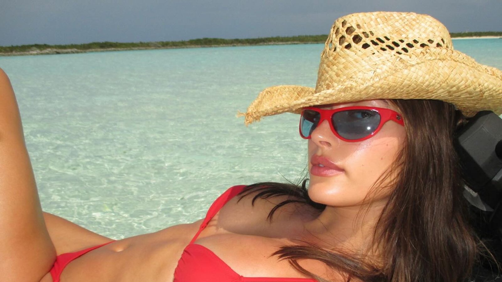 Hailey Bieber wearing a red bikini by Tropic of C and a straw hat